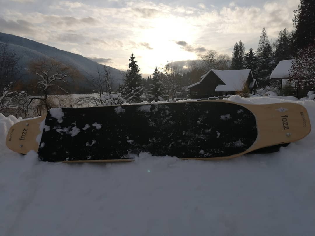 Longboard Fozz sur mesure avec nez et talon en érable visible, posée sur la neige